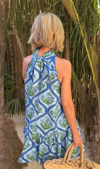 Woman wearing a blue and green patterned dress standing in a natural setting with plants.
