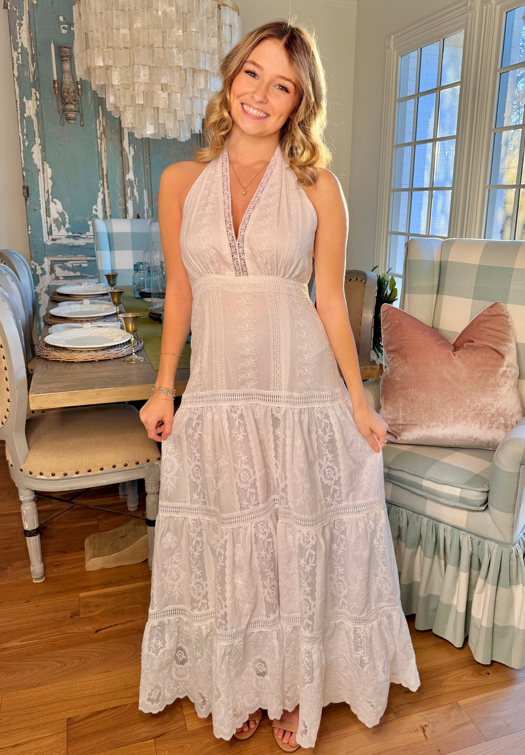 Woman in a white lace dress standing in a living room.