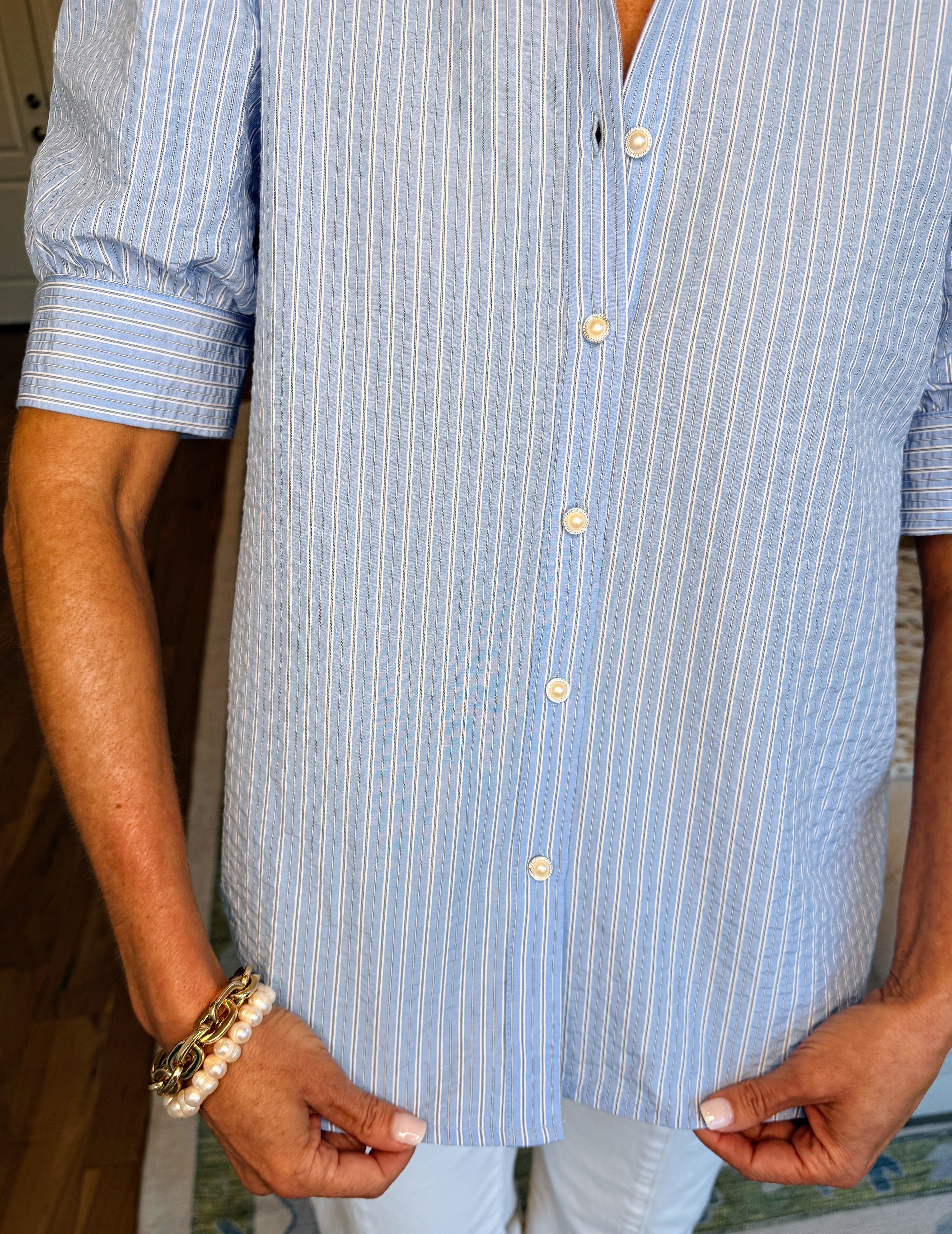 Person wearing a blue and white striped shirt with rolled-up sleeves.
