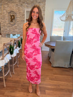 Woman in a pink floral dress standing in a dining room.
